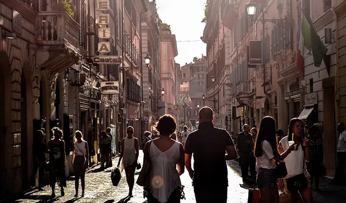 A couple walking down a busy street in Europe surrounded by tourists and locals