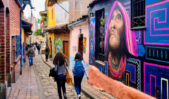 two women walking through streets of graffiti in Bogota
