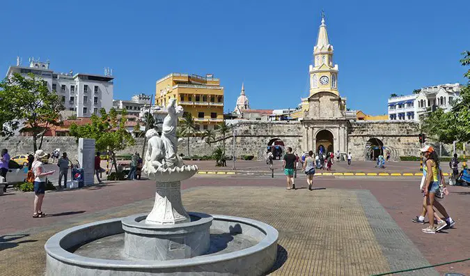 people walking around a plaza with a fountain in Cartagena, Colombia