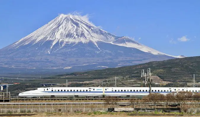 A super fast bullet train rocketing past a snow-capped Mount Fuji in Japan