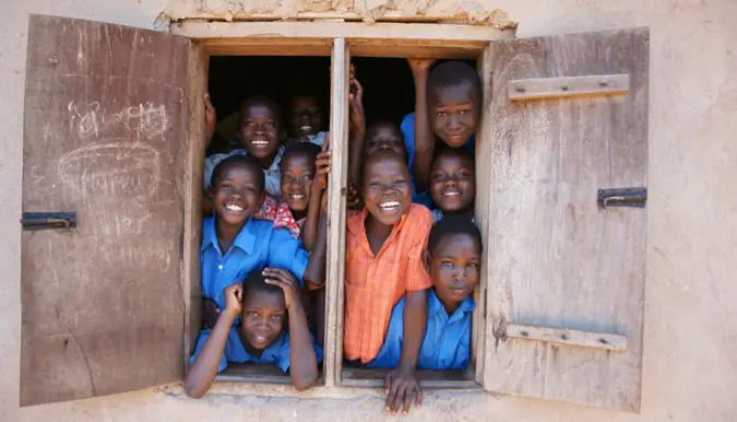 Smiling school children in Africa looking out of a classroom window