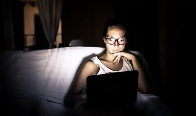 Serious female traveler using her laptop in the dark